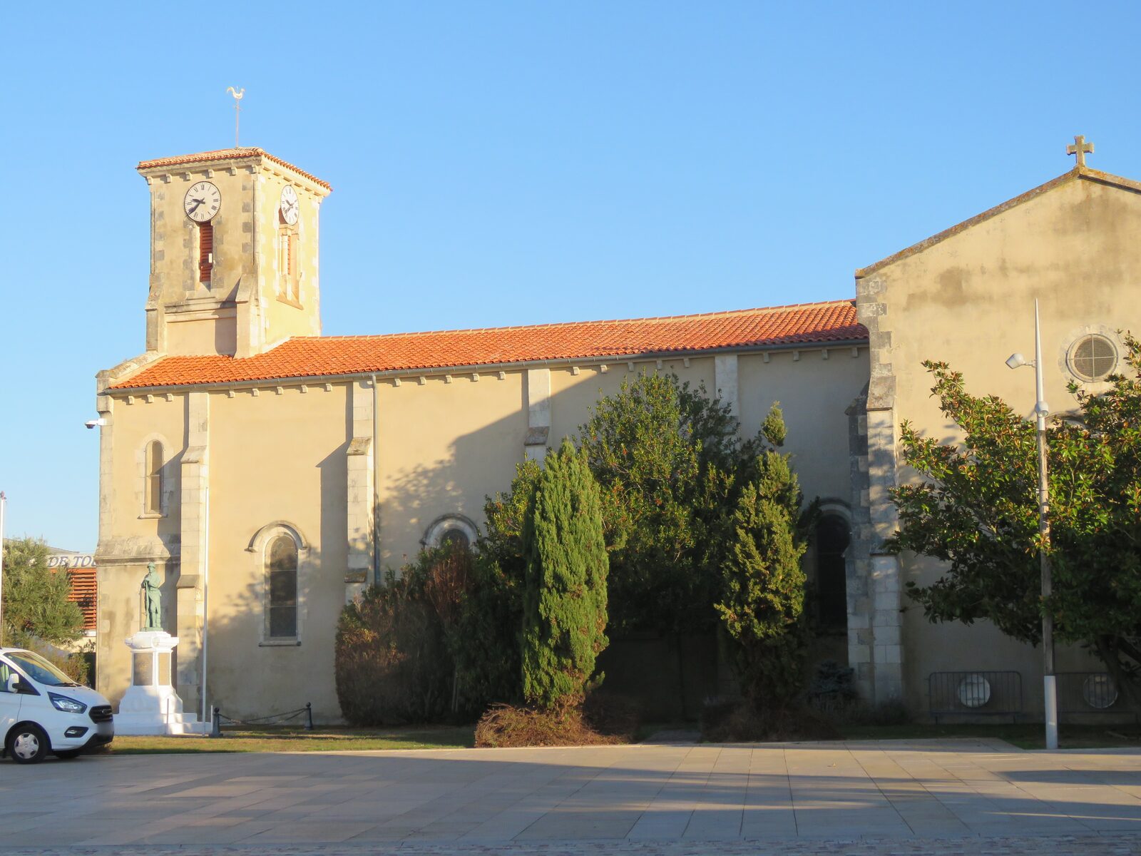 L'église Saint-Nicolas et le monument aux morts, au bourg de La Tranche-sur-Mer, sous un ciel bleu